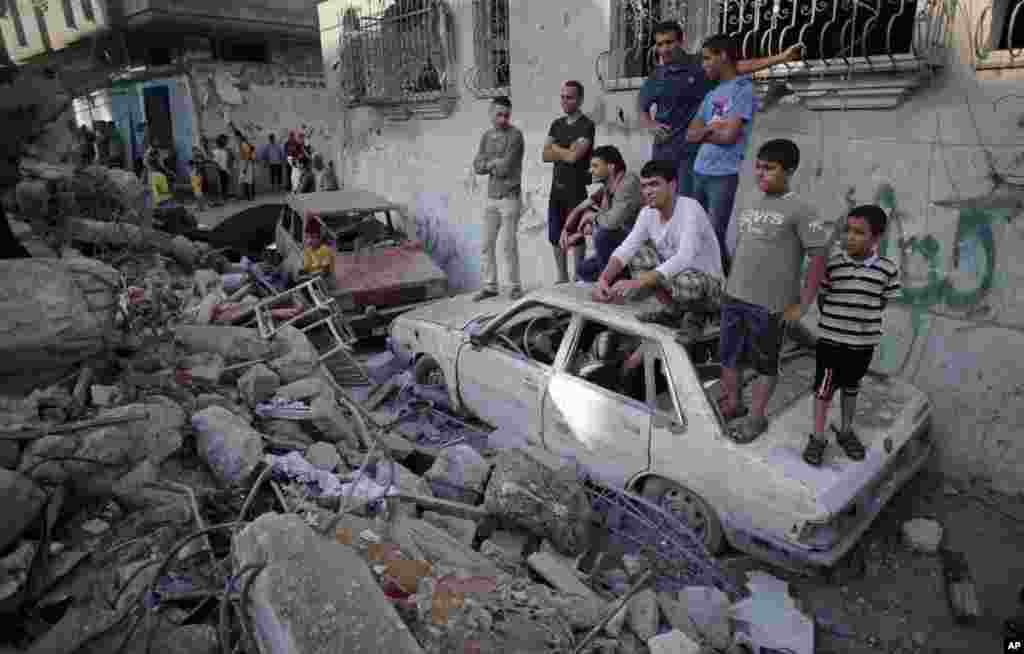 Palestinians look at the damage of a destroyed house where five members of the Ghannam family were killed in an Israeli missile strike early morning in Rafah refugee camp, southern Gaza Strip, July 11, 2014.