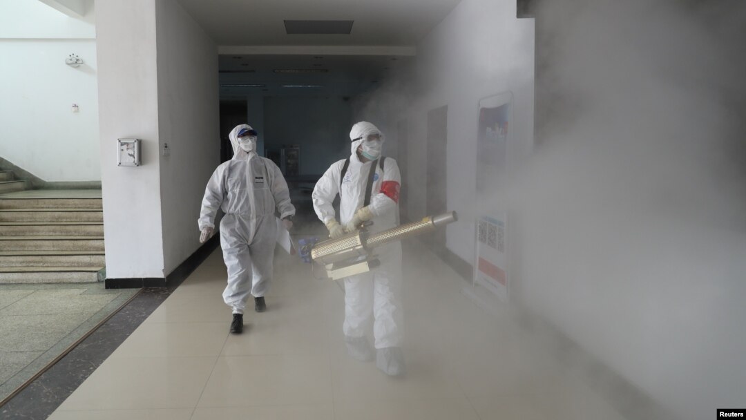 Dos voluntarios desinfectan un complejo residencial en la ciudad china de Wuhan, considerada como el epicentro del brote del coronavirus, el 22 de febrero de 2020.