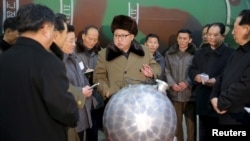 김정은 북한 국방위원회 제1위원장이 핵무기 연구 부문 과학자, 기술자들을 만나 핵무기 병기화 사업을 지도하는 모습을 지난달 9일 조선중앙통신이 보도했다. 사진 아래쪽에 핵탄두 기폭장치 추정 물체가 보인다. (자료사진)