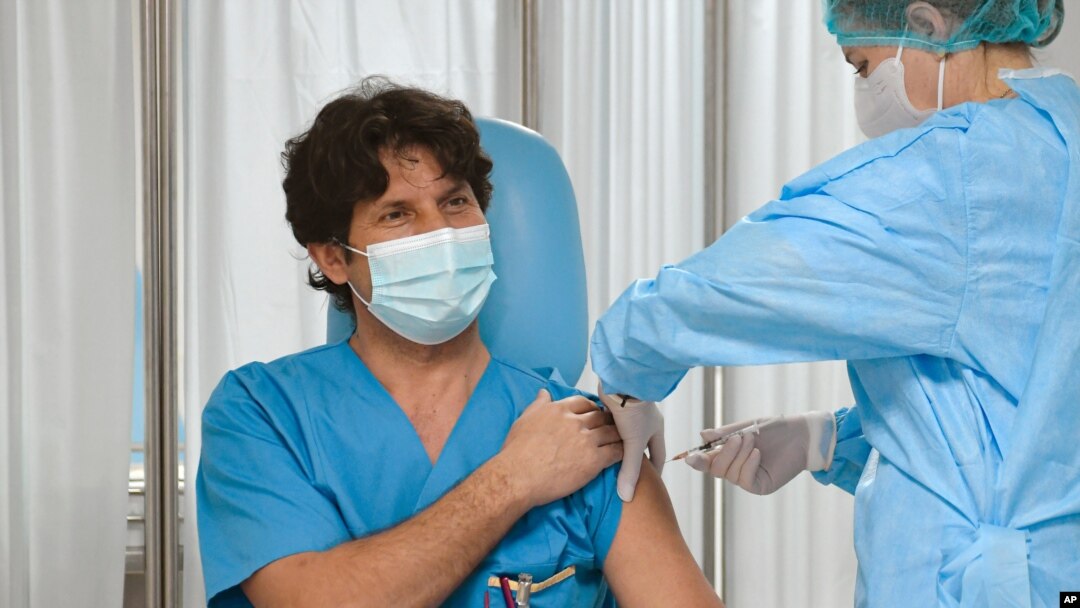 A man gets a COVID-19 vaccine among the first administered in the country in Bucharest, Romania, Sunday, Dec. 27, 2020. Romania has started its national vaccination campaign. (AP Photo/Andreea Alexandru)