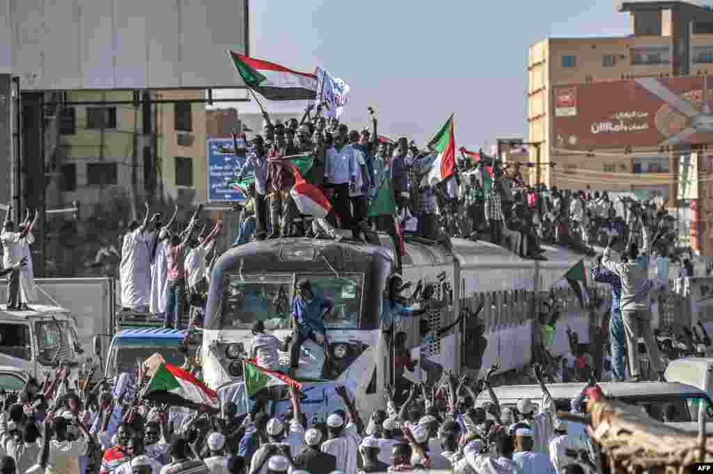 Sudanese protesters from the city of Atbara, sitting atop a train, arrive at the Bahari station in Khartoum. Many demonstrators perched on the roof of the train, waved Sudanese flags as it chugged through north Khartoum's Bahari railway station before winding its way to the protest site, an AFP photographer said.