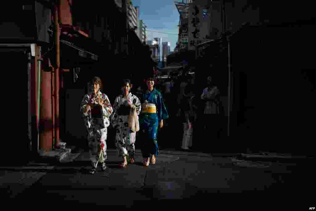 Women wearing kimonos walk along a street in Tokyo's Asakusa district, Japan.