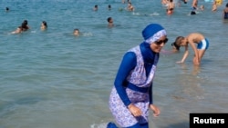 FILE - A woman wearing a burkini walks in the water on a beach in Marseille, France, Aug. 27, 2016. 