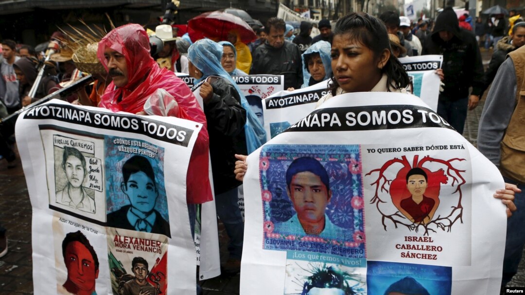 Relatives and friends hold banners with images of some of the 43 missing students as they march in Mexico City to mark the first anniversary of the students' disappearance, Sept. 26, 2015.