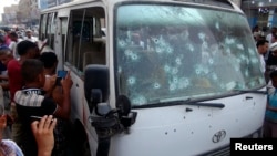 People gather around a bus after it was attacked by gunmen in Yemen's southern port city of Aden, June 15, 2014. 