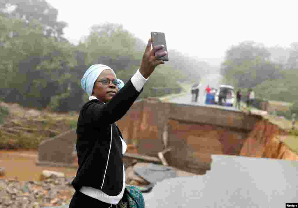 A woman takes a selfie at a washed away bridge along Umvumvu river after Cyclone Idai swept through Chimanimani, Zimbabwe, March 18, 2019.