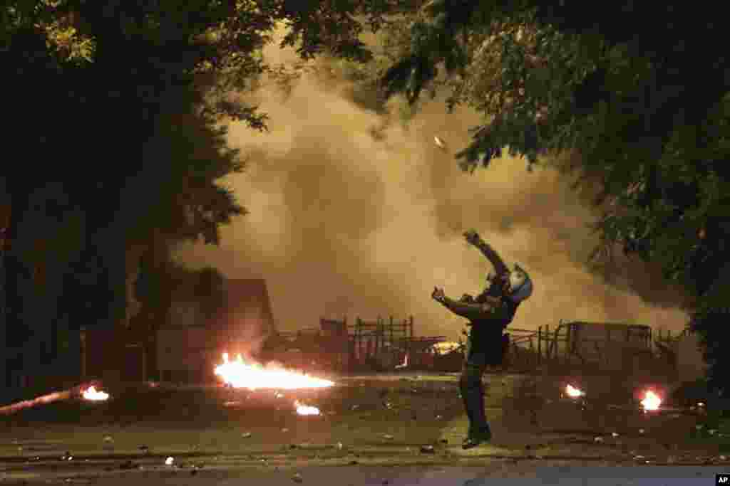 A riot policeman throws a stun grenade during clashes outside the Polytechnic University in Athens, Greece, Nov. 17, 2018, on the 45th anniversary of a student uprising against the country's then-ruling military regime.