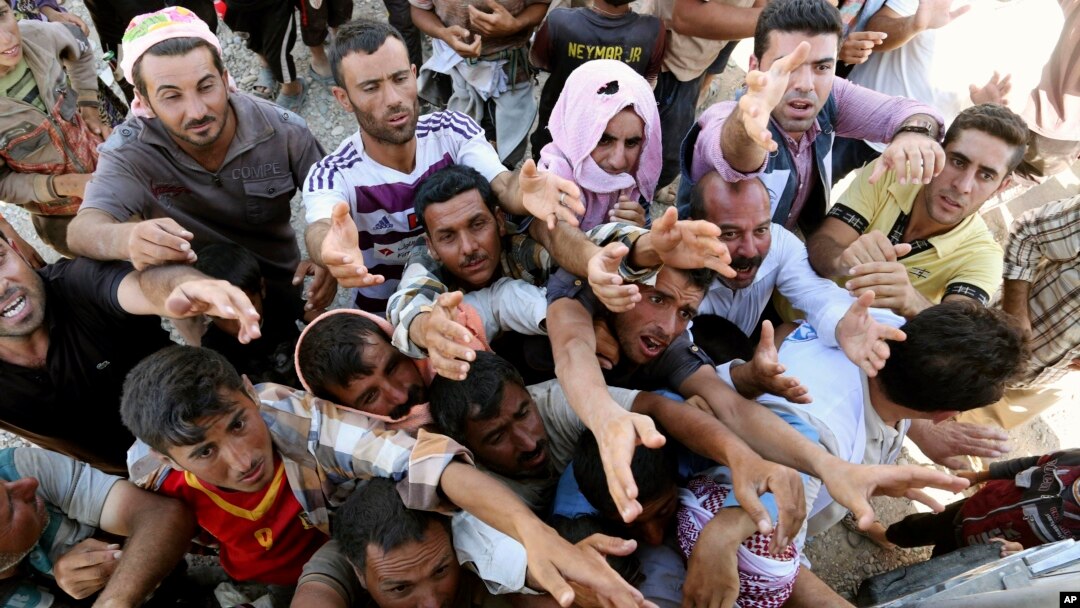 Displaced Iraqis from the Yazidi community gather for humanitarian aid at the Syria-Iraq border at Feeshkhabour border point, northern Iraq, Aug. 10, 2014.