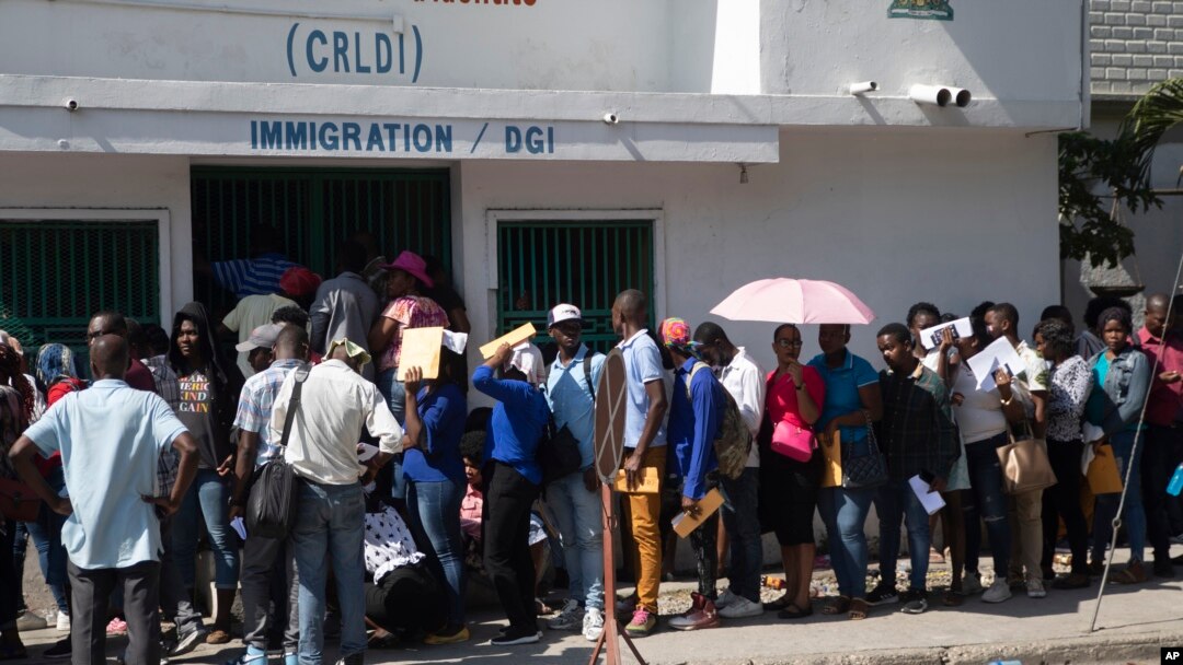 Un grupo de haitianos hacen una fila frente a una oficina de inmigración mientras esperan su turno para solicitar un pasaporte, el martes 10 de enero de 2023, en Puerto Príncipe, Haití. (AP Foto/Odelyn Joseph)