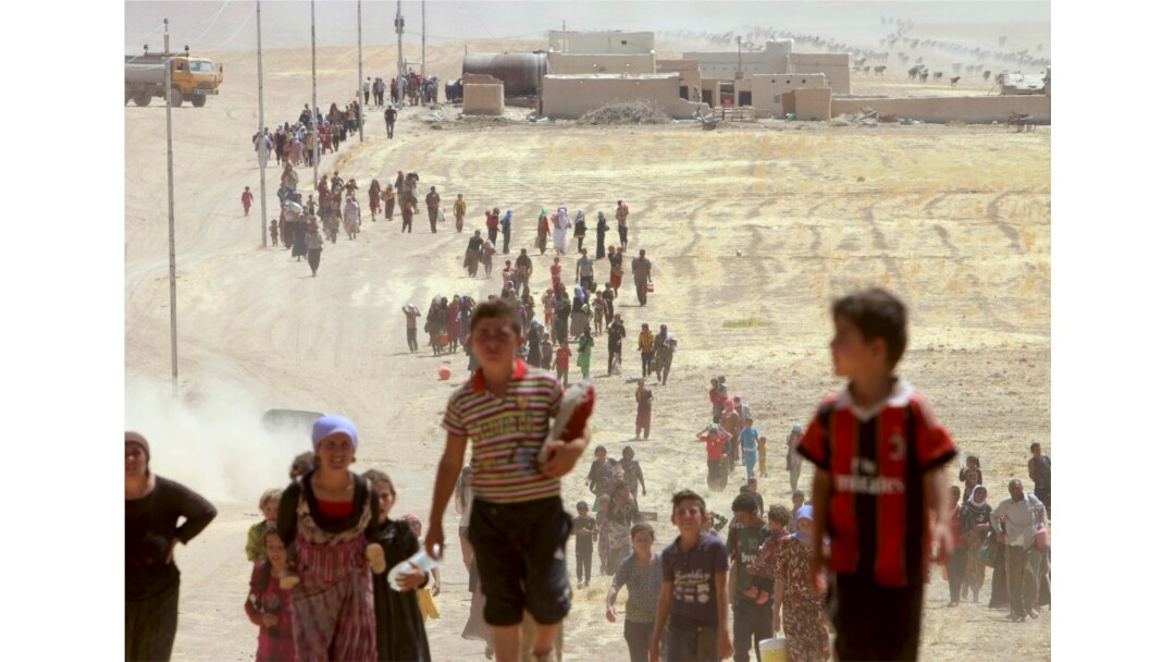 FILE - Displaced people from the Yazidi sect, fleeing violence from forces loyal to Islamic State militants in Sinjar, walk toward the Syrian border on the outskirts of Sinjar mountain.