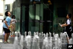 孩子們在北京街頭的噴水池玩水。（2023年7月1日）