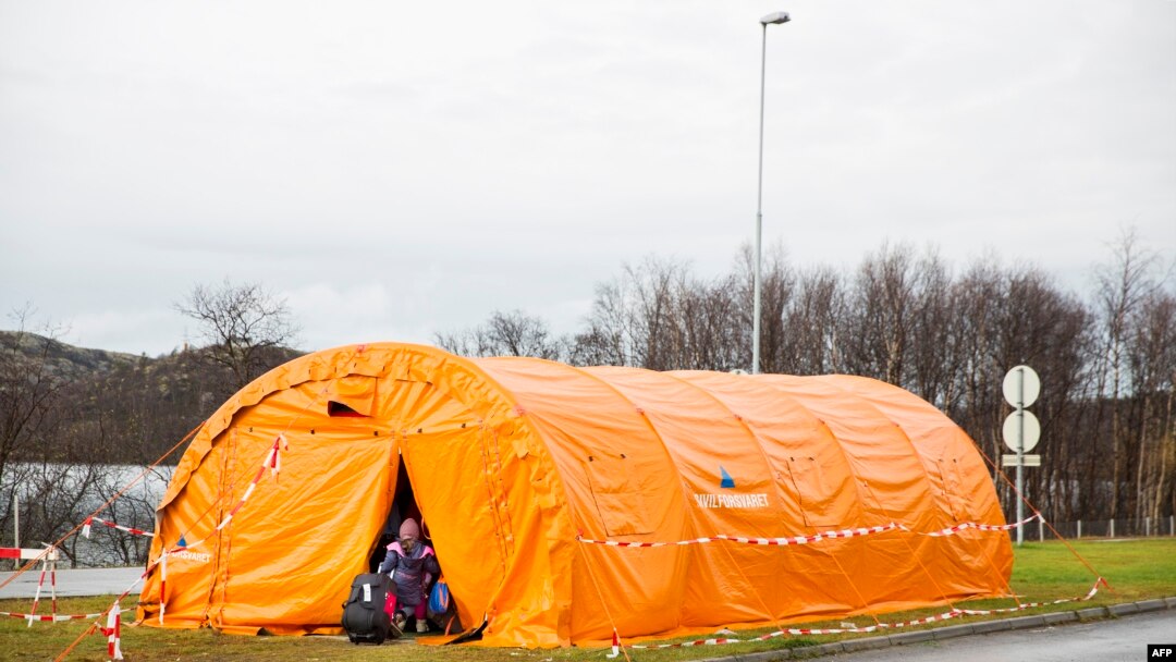FILE - A girl enters a the temporary reception center for refugees at Storskog border station near Kirkenes in northern Norway at the Norway-Russia border, on Oct. 13, 2015. 
