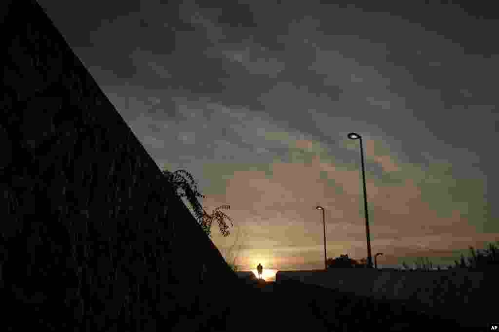 A man walks over a bridge as the sun sets in Athens, Greece.
