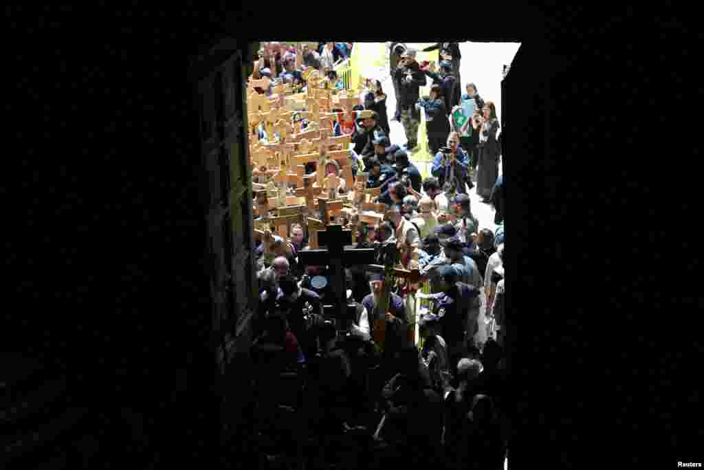Orthodox Christian worshippers carry wooden crosses into the Church of the Holy Sepulchre during Good Friday procession along the Via Dolorosa in Jerusalem's Old City.