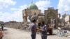 Many areas once controlled by Islamic State militants are still destroyed more than nine months after the battle. Behind these men is the ruins of the al-Nouri Mosque in Mosul, Iraq, May 9, 2018. 
