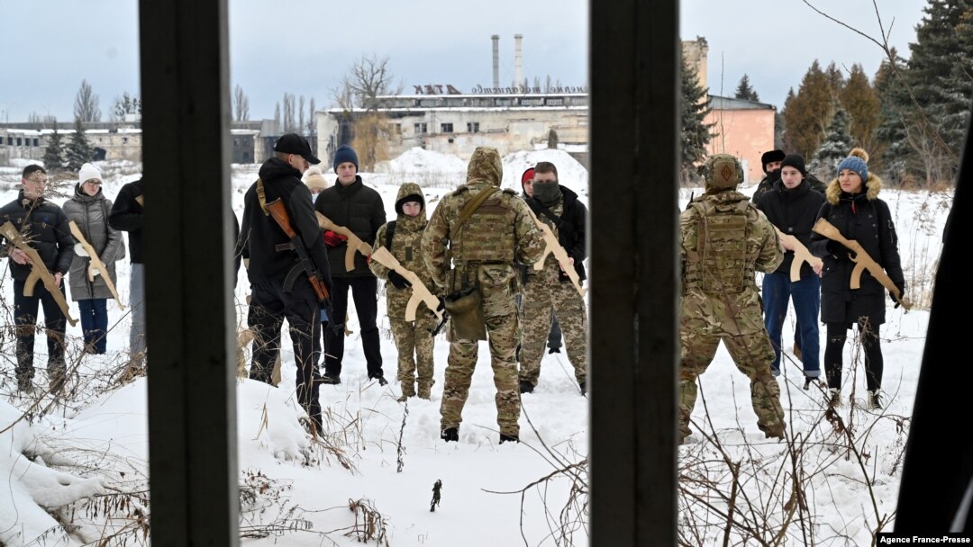 A military instructor teaches civilians holding wooden replicas of Kalashnikov rifles, during a training session at an abandoned factory in the Ukrainian capital of Kyiv on Jan. 30, 2022.