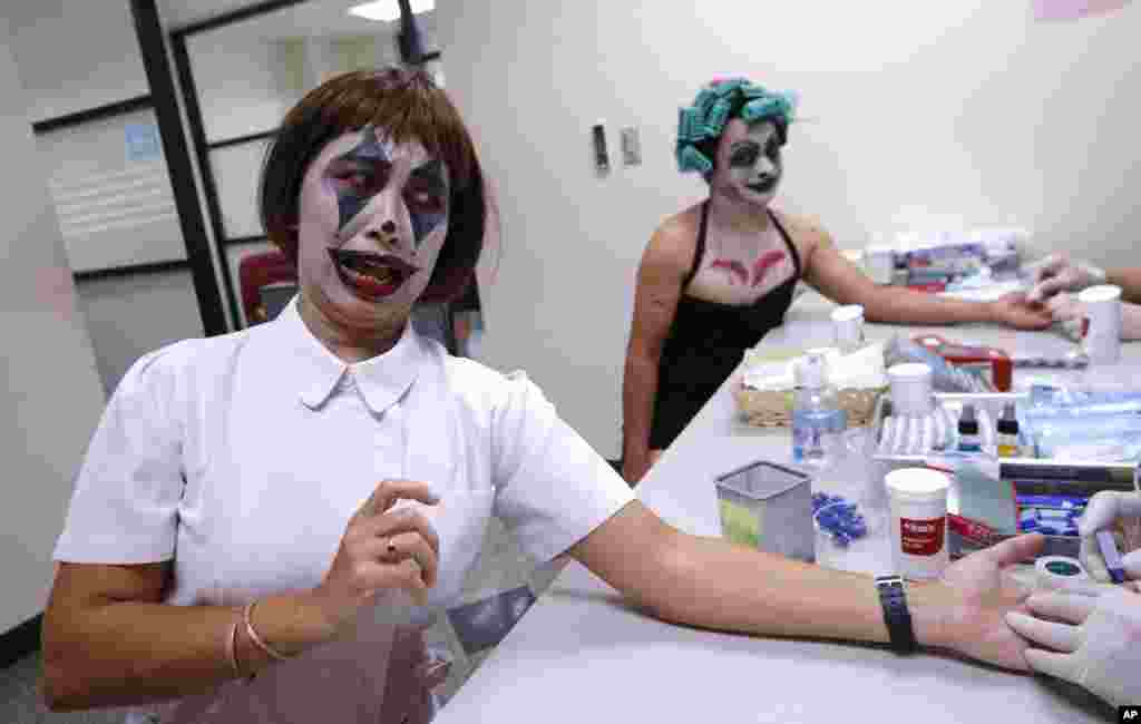 Manful Bumroongton, front, and Thanat Chotrat dressed in a ghost costume for Halloween take blood test before donating blood at the Thai Red Cross in Bangkok, Thailand.
