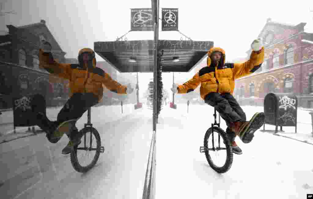 Caleb Seely rides a unicycle on a snow covered sidewalk during a winter storm, Jan. 20, 2019, in Portland, Maine.