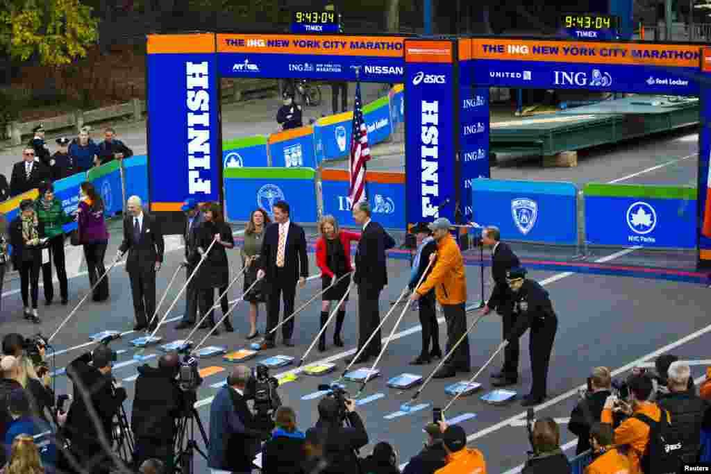 Marathon and government officials take part in the ceremonial painting of the New York City Marathon blue line at Central Park, New York, Oct., 2013.