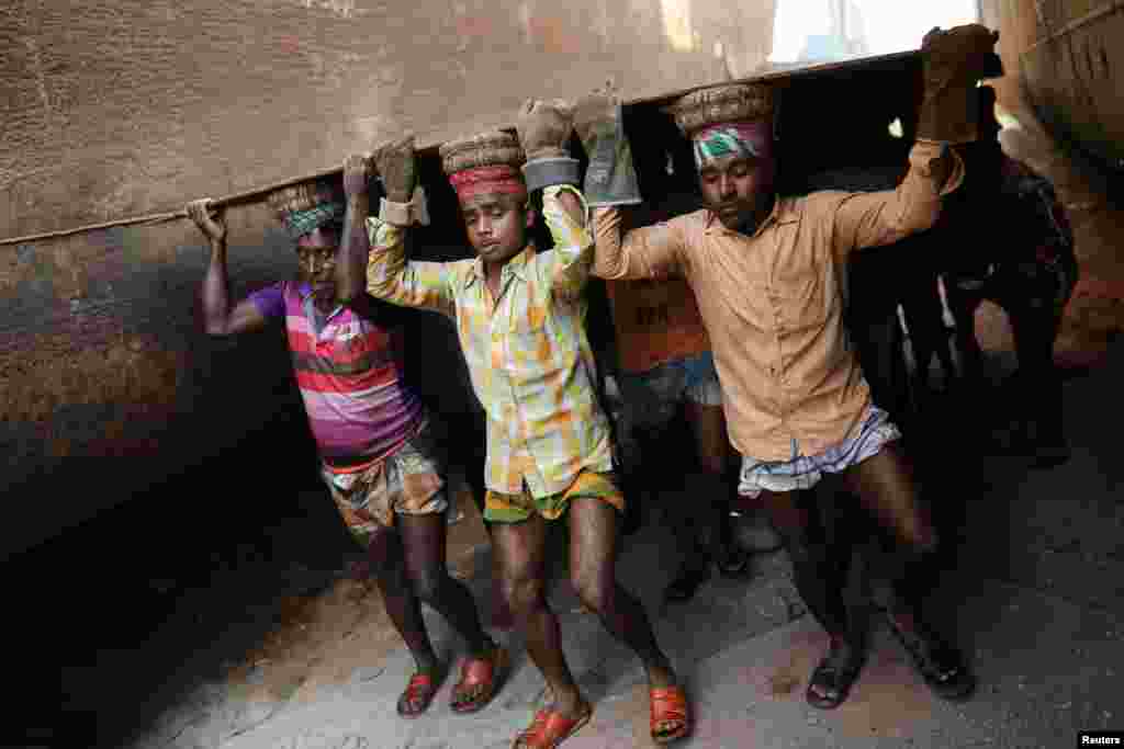 Workers carry a metal sheet at a dockyard in Dhaka, Bangladesh.
