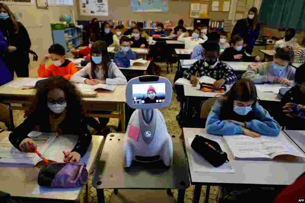 Children work in a classroom while a schoolgirl at home is connected with a "Buddy" tele-education robot at Jules Ferry elementary school in Ormesson-sur-Marne, near Paris.