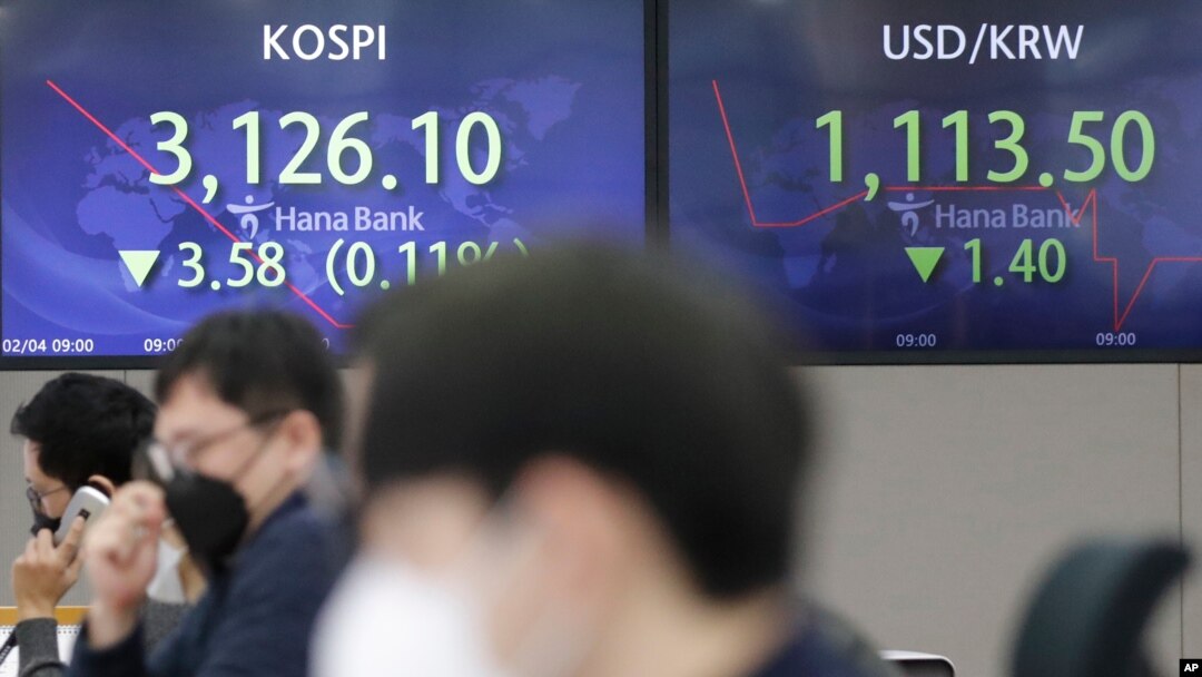 Currency traders watch computer monitors near screens showing the Korea Composite Stock Price Index, left, and the foreign exchange rate between US dollar and South Korean won at the foreign exchange dealing room in Seoul, South Korea, Feb. 4, 2021.