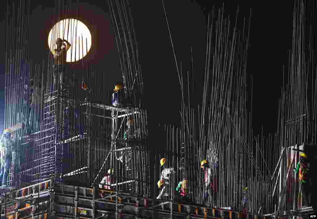 A 'Super Snow Moon' rises as construction laborers work at a building site in Kolkata, India. Super Moon is a term used when a full moon is at or near its closest approach to Earth.