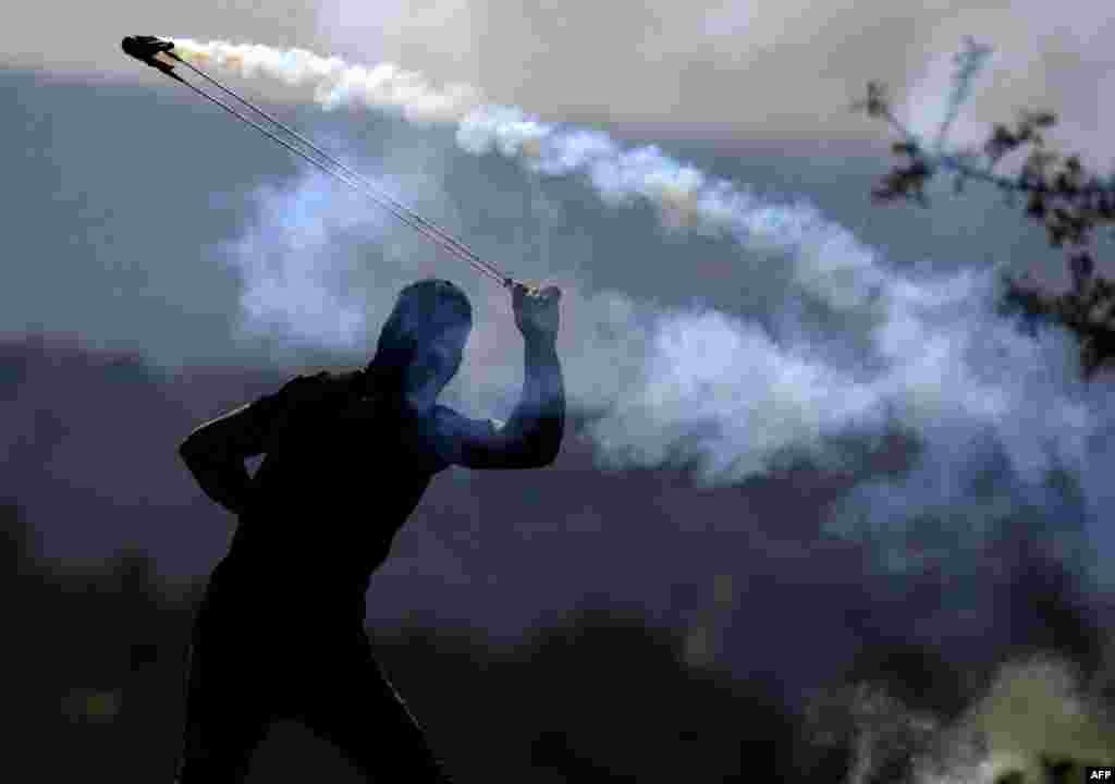 A Palestinian protester throws a tear gas canister towards Israeli soldiers who fired it during a demonstration against Israeli land seizures for Jewish settlements in the occupied West Bank.