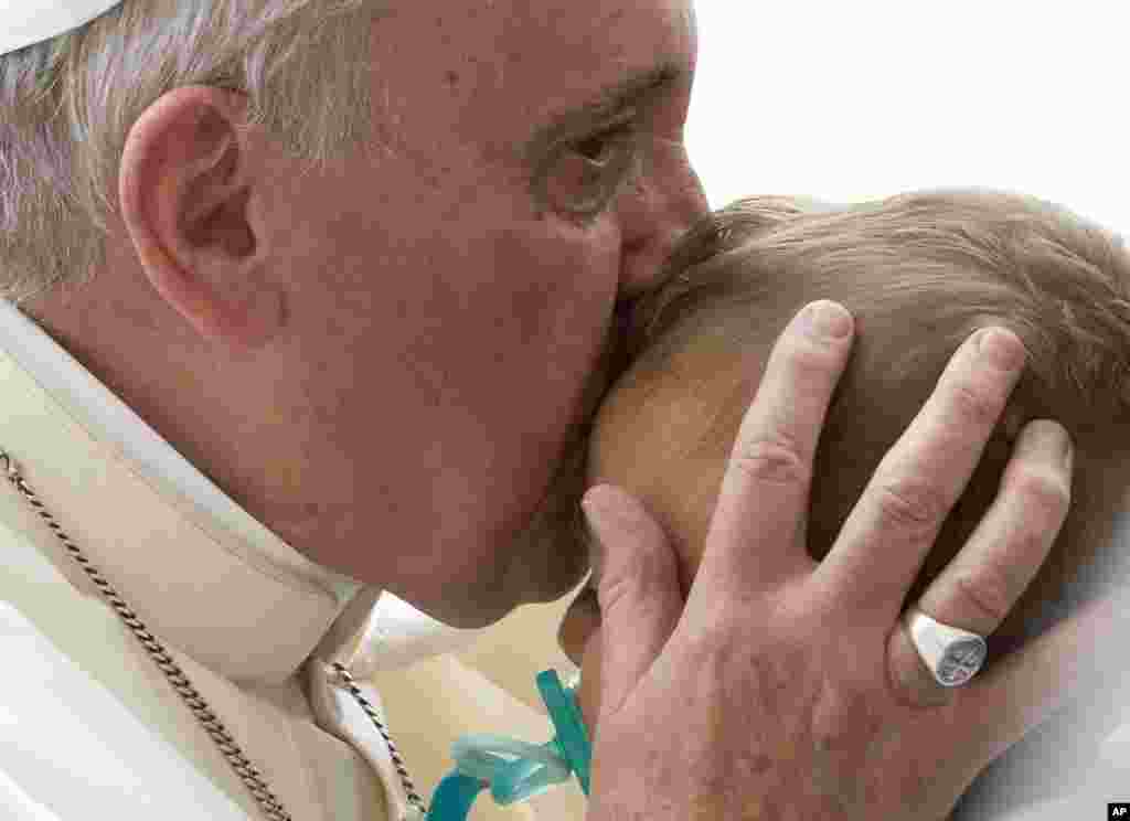 Pope Francis kisses a baby at the end of his weekly general audience in St. Peter's Square at the Vatican.