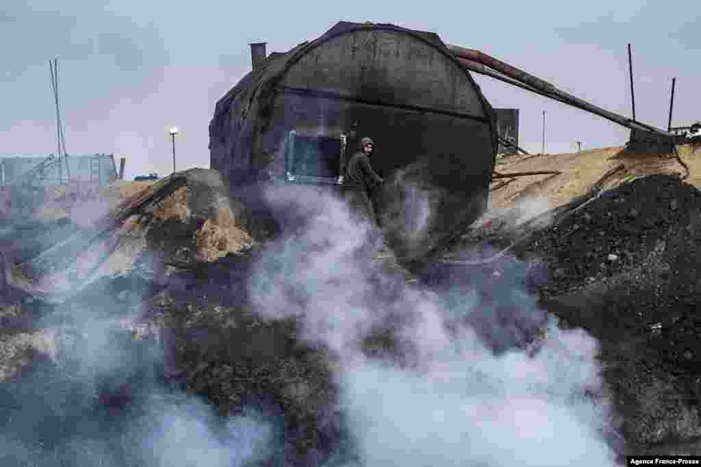 A worker is seen at a primitive oil refinery facility in the town of al-Qahtaniya in Syria's Kurdish-controlled northeastern Hasakah province, near the border with Turkey, Nov. 15, 2021.