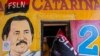  (ARCHIVOS) En esta foto de archivo tomada el 17 de julio de 2020, un hombre sostiene una bandera del Frente Sandinista de Liberación Nacional (FSLN) junto a un mural que representa al presidente de Nicaragua, Daniel Ortega. Foto por INTI OCON / AFP)