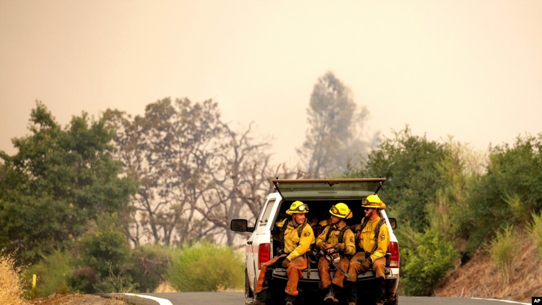 Firefighters ride in the back of a pickup truck while battling the LNU Lightning Complex fires, Aug. 23, 2020, in unincorporated Lake County, Cailf. 