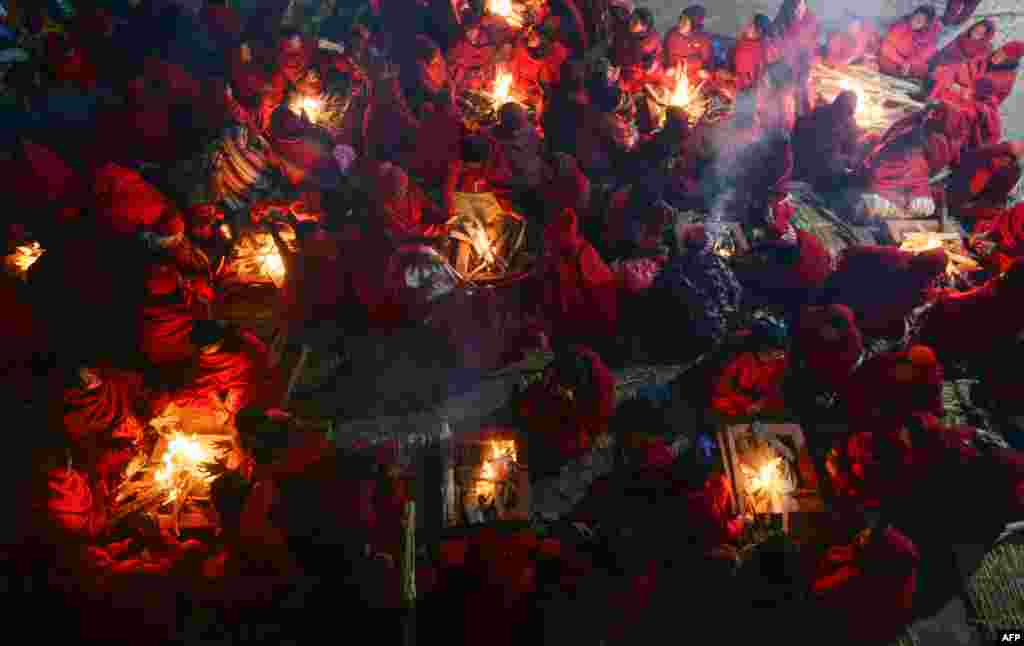 Hindu women warm themselves beside fires before taking a bath in the holy Shali River on the outskirts of Kathmandu to mark the Swasthani Brata Katha festival, Nepal.