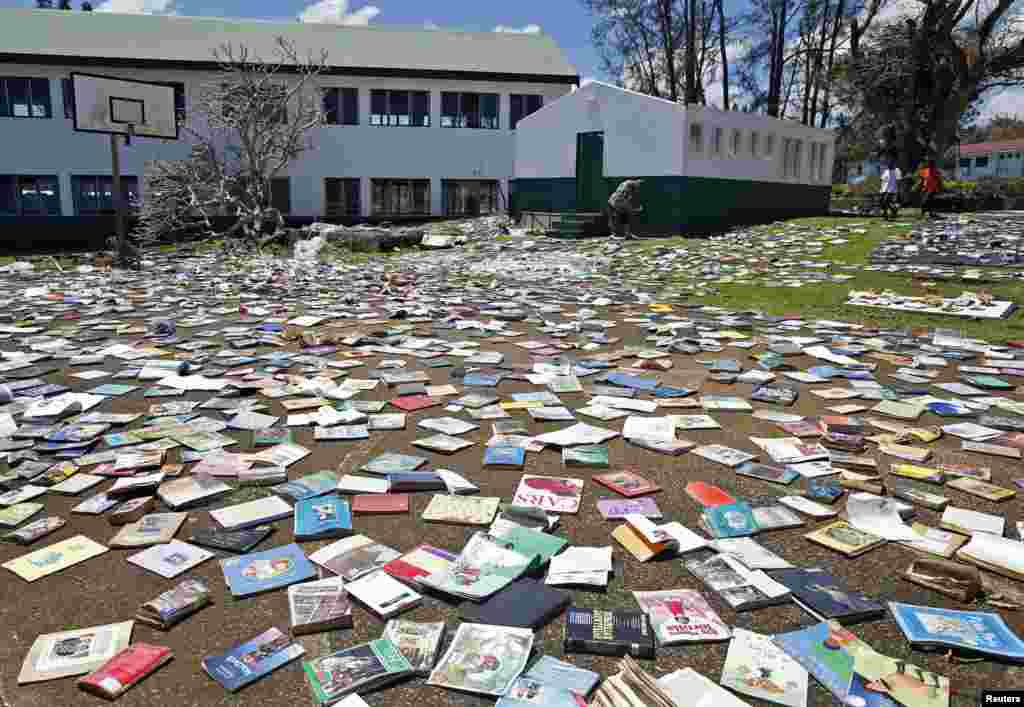 Paul Alexander Hatyay (C), the headmaster, and teacher of Central School, lays out books to dry in the sun after the roof of the school's library was blown away by Cyclone Pam in Port Vila, the capital city of the Pacific island nation of Vanuatu. 