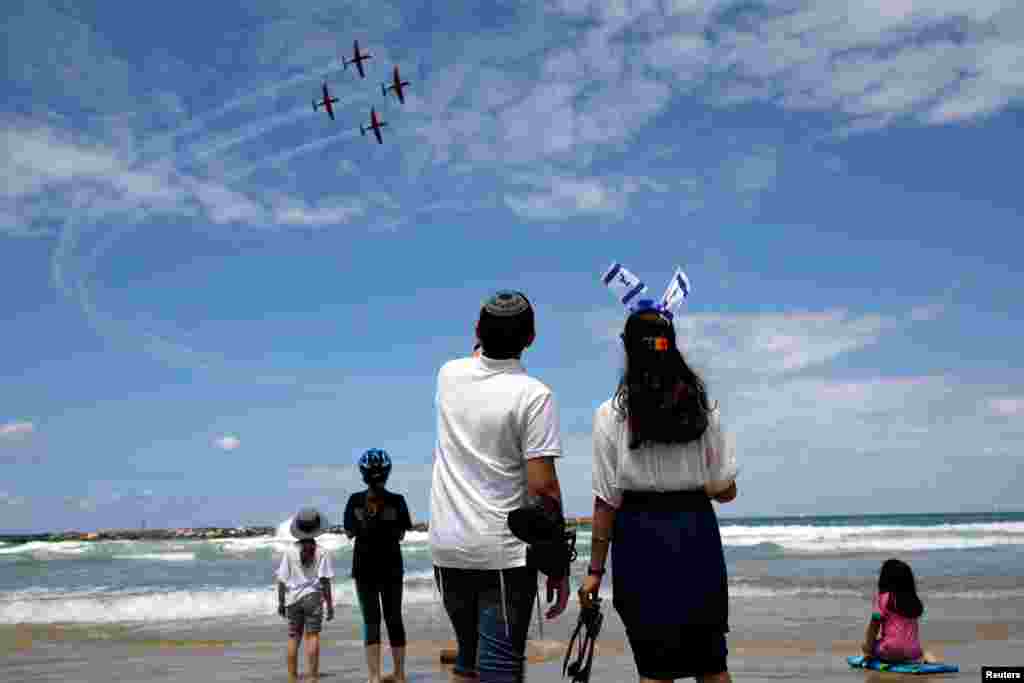 People watch as Israeli Air Force planes fly over the Mediterranean Sea during an aerial show as part of the celebrations for Israel's Independence Day marking the 71st anniversary of the creation of the state, in Tel Aviv.