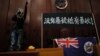 一名進入香港立法會的抗議者站在掛在立法會內的香港殖民地旗幟旁使用擴音喇叭講話。（2019年7月1日） 