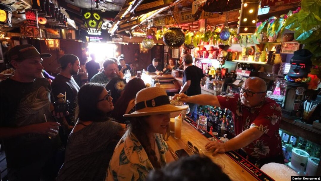 In this Wednesday, July 7, 2021, file photo, patrons enjoy cold tropical cocktails in the tiny interior of the Tiki-Ti bar as it reopens on Sunset Boulevard in Los Angeles.(AP Photo/Damian Dovarganes, File)