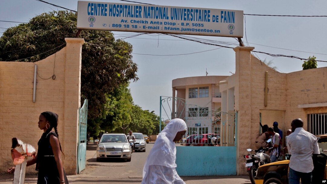Women walk past the entrance to the University Hospital Fann, where a man is being treated for symptoms of the Ebola virus in Dakar, Senegal, Aug. 29, 2014.