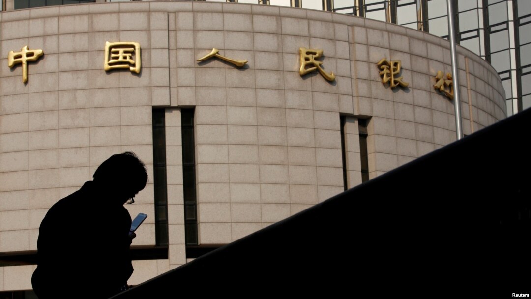 資料照：一名男子坐在中國人民銀行總部大樓外。
