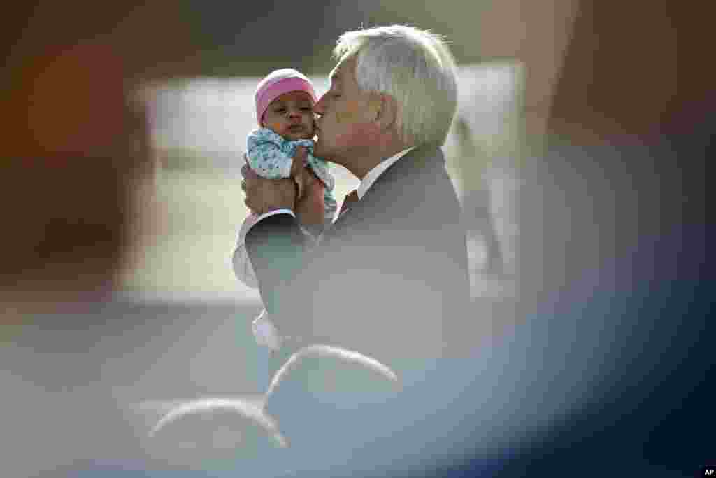 Chile's President Sebastian Pinera kisses a baby as he receives a group of repatriates at the international airport, in Santiago.