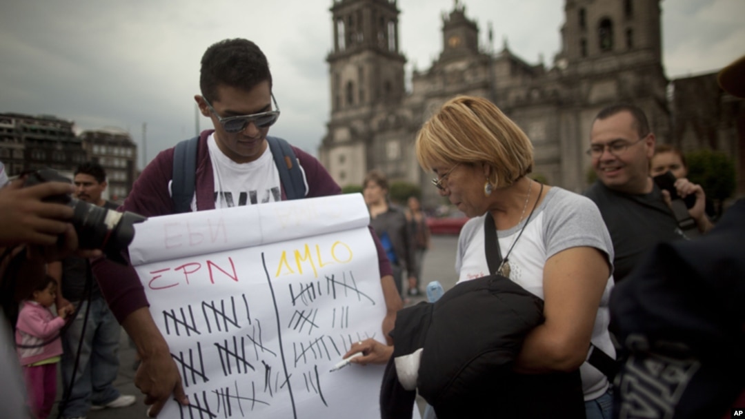 Jóvenes mexicanos muestran en el Zócalo de la capital un cartel con la puntuación de los candidatos presidenciales, según sondeos.