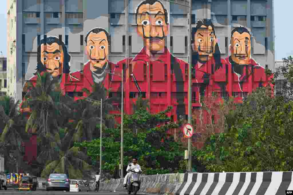 Commuters drive past a mural depicting characters from the Spanish TV show "Money Heist" in Mumbai.