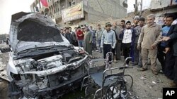 Mutane suna kallon motar da ta tarwatse a wurin da aka kai harin bom kan wata runfar da ake jana'iza a yankin 'yan Shi'a dake Bagadaza, Iraq.