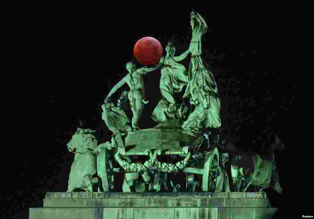 The moon is seen on the top of the Cinquantenaire arch during a total lunar eclipse, known as the "Super Blood Wolf Moon", in Brussels, Belgium.