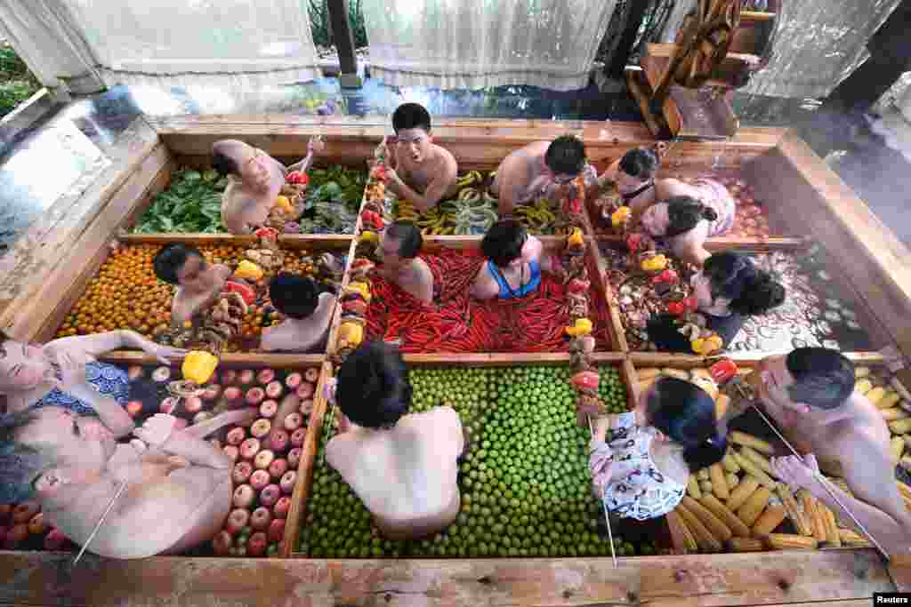 People enjoy a barbecue as they bath in a hotpot-shaped hot spring filled with fruits and vegetables, at hotel in Hangzhou, Zhejiang province, China.