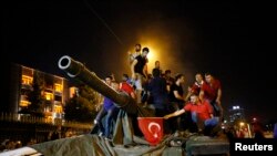 People stand on a Turkish army tank in Ankara, Turkey, July 16, 2016. 