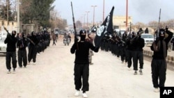 FILE - This undated file image posted on a militant website, Jan. 14, 2014, which has been verified and is consistent with other AP reporting, shows fighters from the al-Qaida linked Islamic State of Iraq and the Levant (ISIL) marching in Raqqa, Syria. (AP Photo/Militant Website)