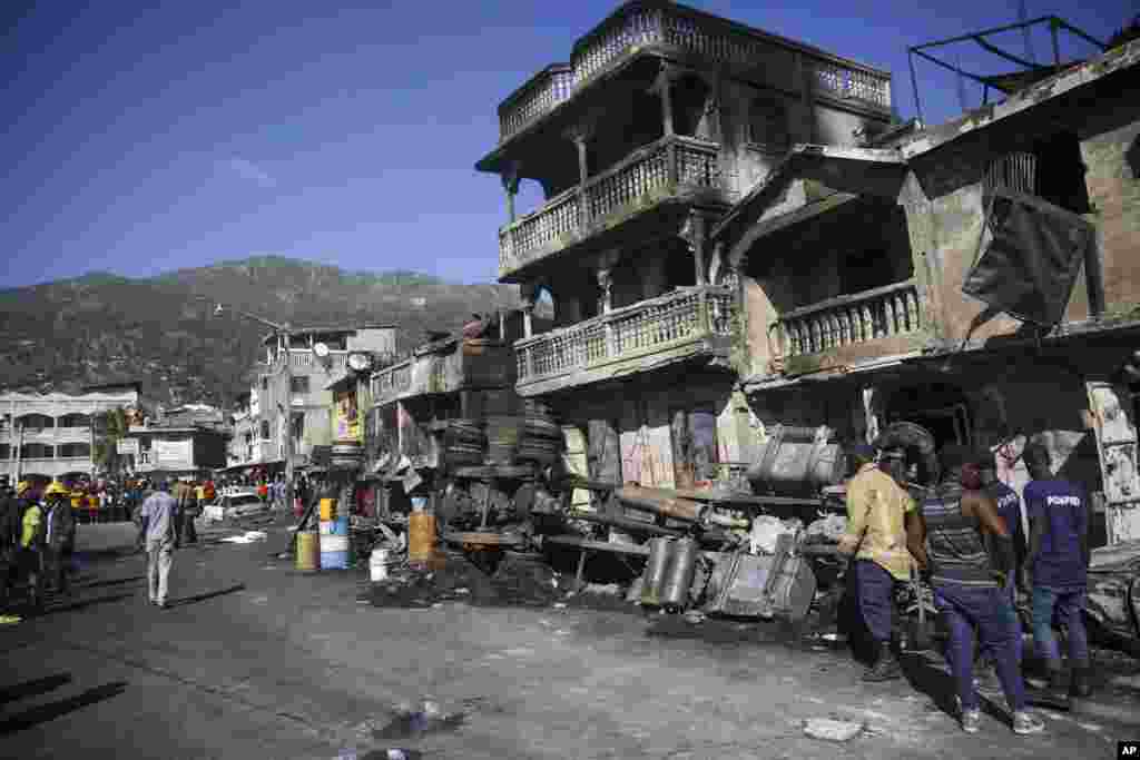 Firefighters stand next to what remains of a truck that was carrying gasoline after it overturned and exploded in Cap-Hatien, Haiti. The explosion engulfed cars and homes in flames, killing more than 50 people and injured dozens of others. 