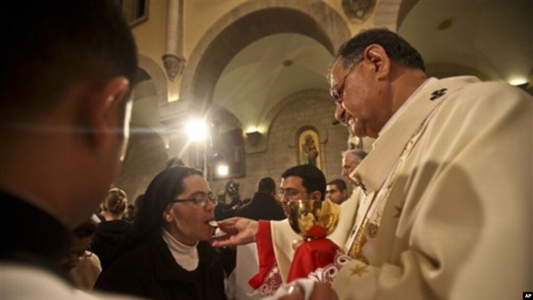 A nun takes communion from Latin Patriarch of Jerusalem Fouad Twal during Christmas midnight mass at the Church of the Nativity, traditionally believed to be the birthplace of Jesus Christ, in the West Bank town of Bethlehem early Saturday, Dec. 25, 2010.