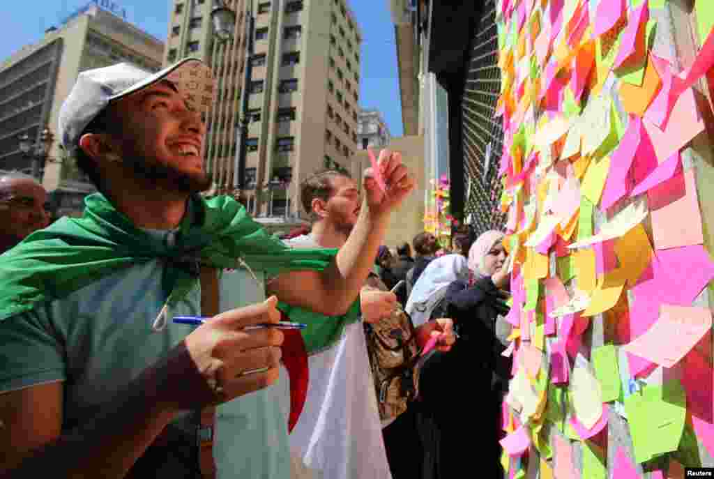 People write slogans and messages on sticky notes during a protest demanding immediate political change in Algiers, Algeria after ailing President Abdelaziz Bouteflika announced he is delaying the April 18 election and won't seek another term.